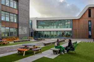 Students are sitting on the bench in front of the modern building at the Bangor University