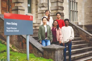 Students standing in front of Bangor University Business school sign