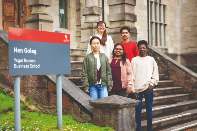 Students standing in front of Bangor University Business school sign