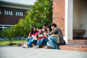 Group of students sat on steps looking at a book together