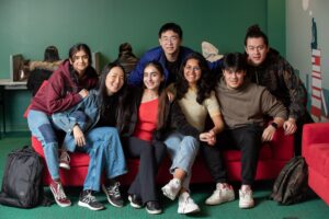Group of Coquitlam College students sat on red sofa looking at camera