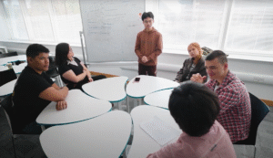 Group of international students collaborating in a classroom at Bangor University, working together on a project near a whiteboard